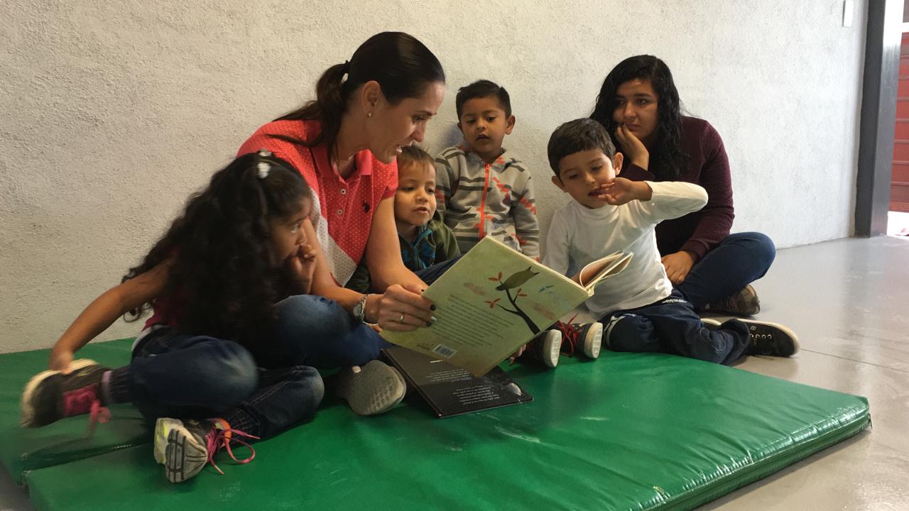 Educadora compartiendo una lectura con niñas y niños